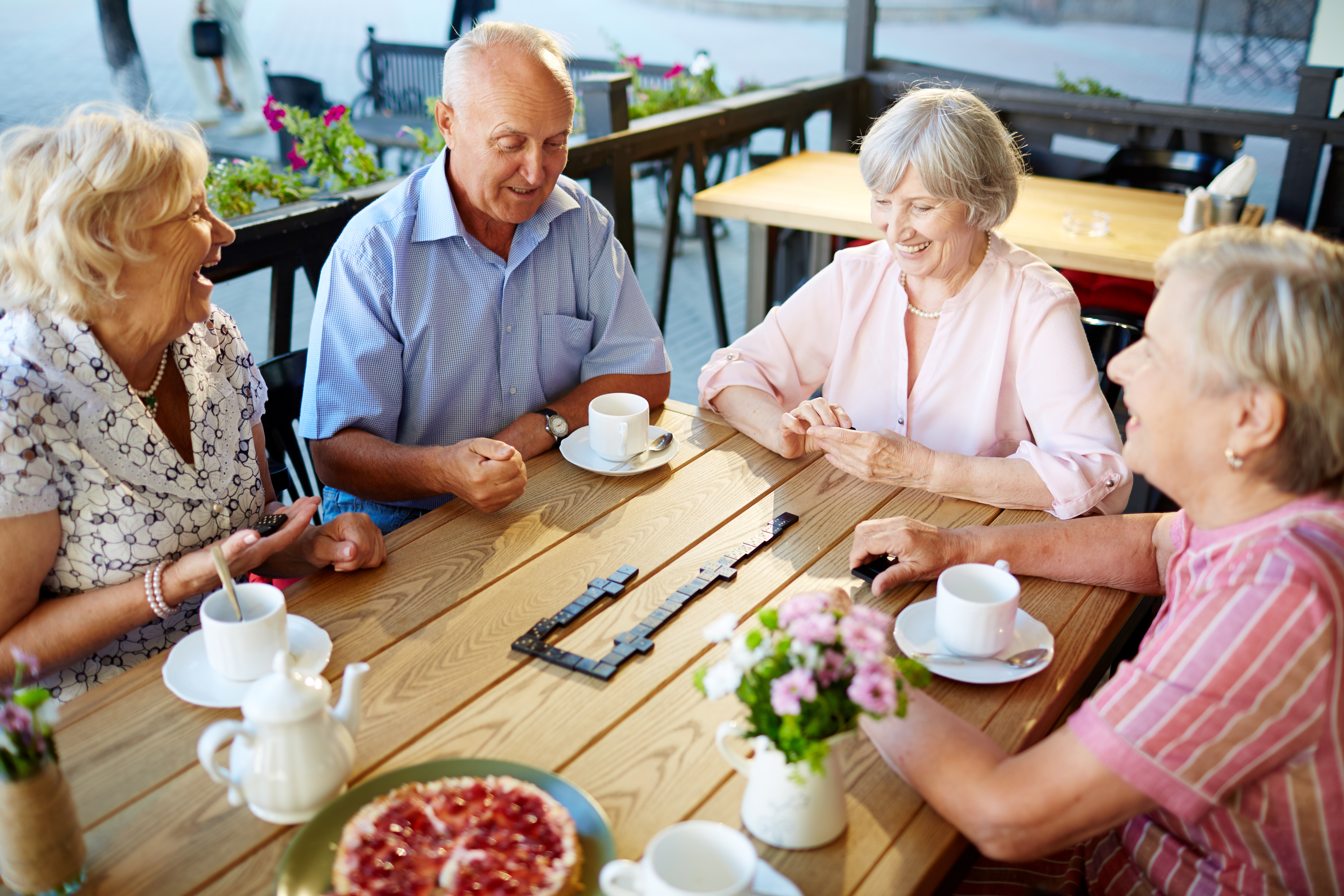 Happy senior friends playing dominoes at leisure